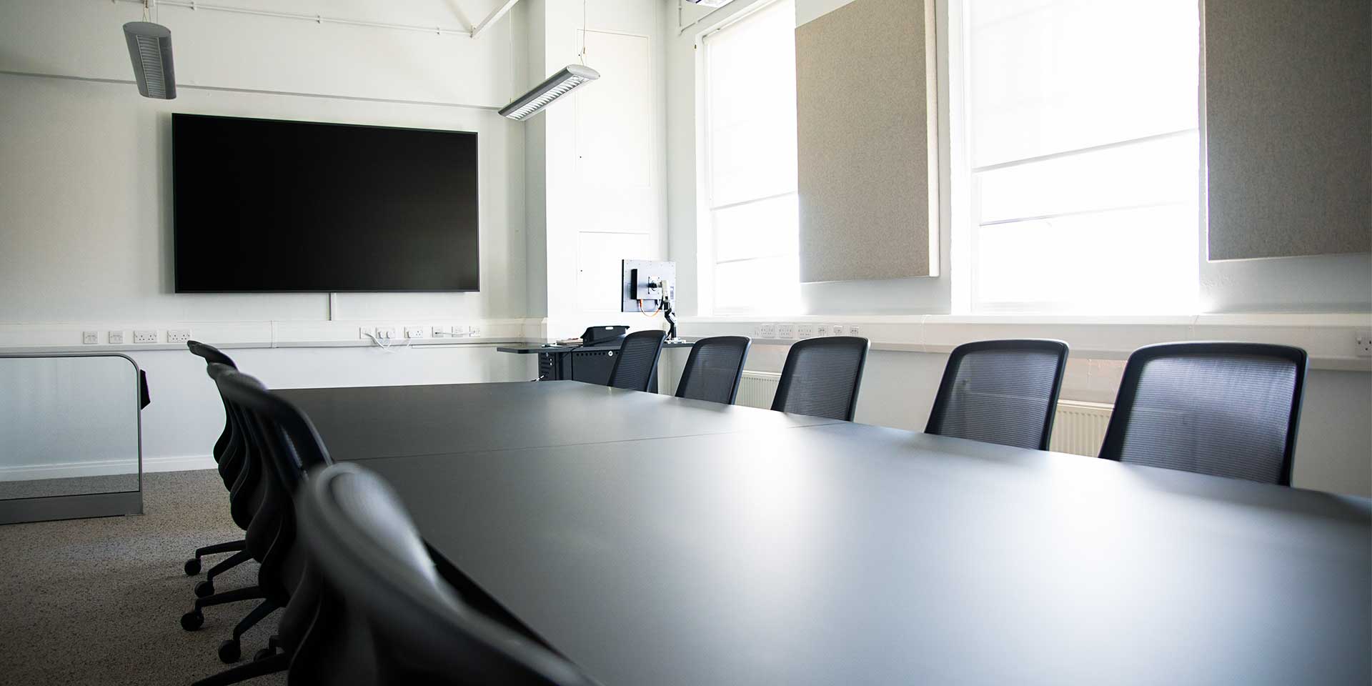 A modern seminar or conference room equipped with a large screen, integrated cabling, and acoustic wall panels.