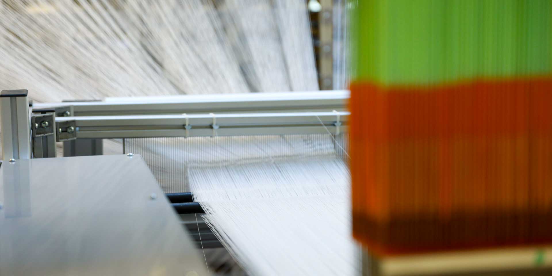 High-precision textile processing machinery guiding yarn strands through thread guides.